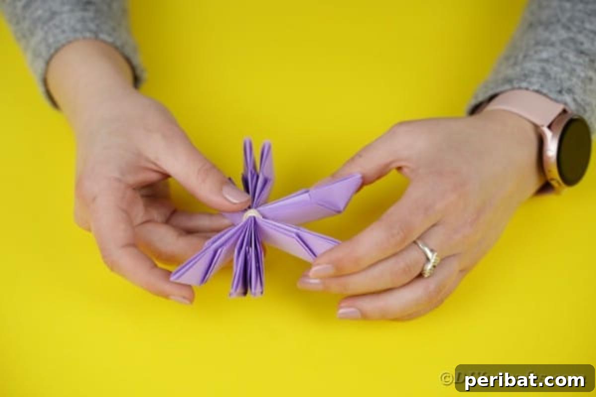 Purple paper segments fanned out to start forming a flower shape.