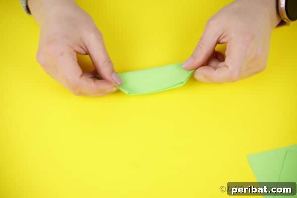 Green paper folded again, forming a compact segment.