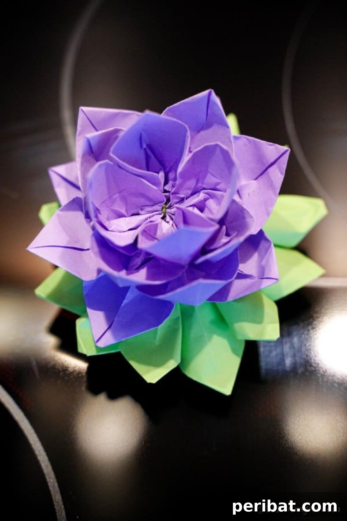 Another view of the purple paper lotus, highlighting its detailed layers against a dark background.