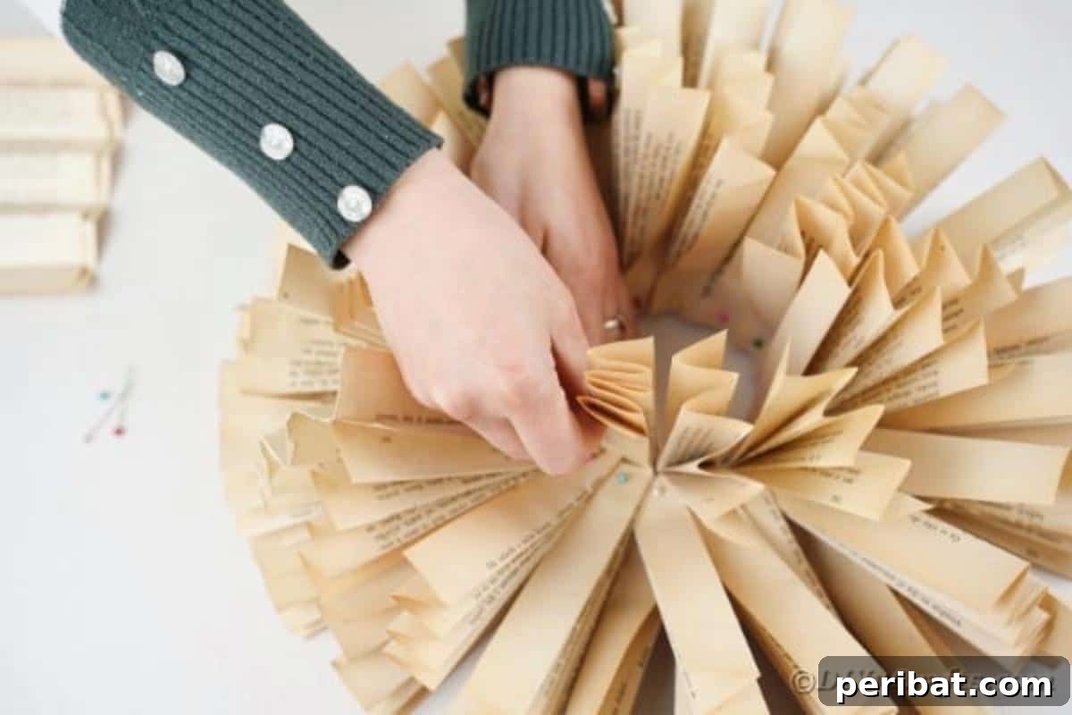 The process of adding more paper fans to the wreath form, building up layers to create a full, voluminous paper flower