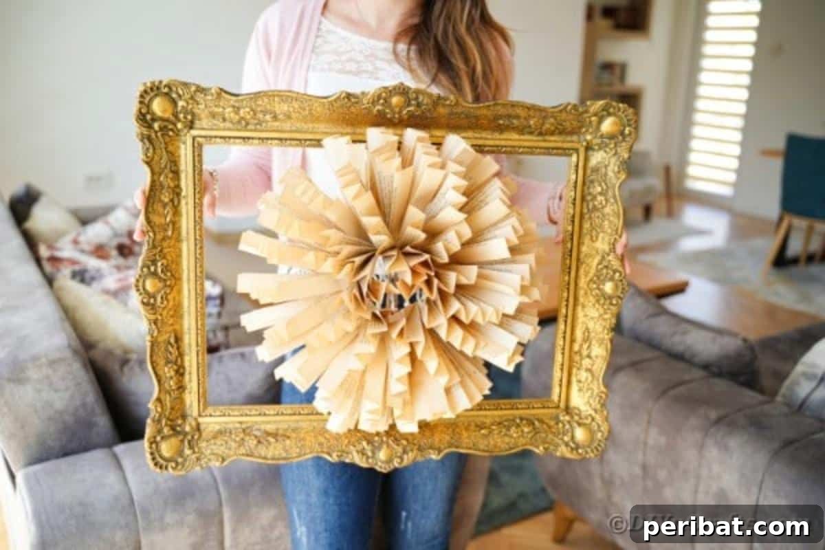 A person proudly holding up the completed old book page paper flower framed art piece