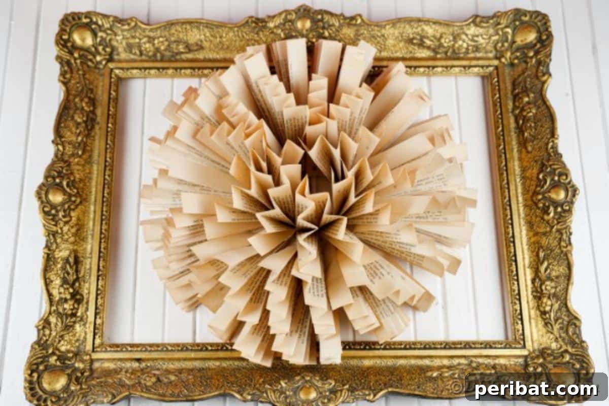 Close-up of a book page fan flower nested within a gold ornate frame, set against white wooden boards